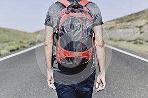 Backpacker man walking by a secondary road