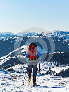 Backpacker mountain hiker man with crampons on a snowy mountain ridge from the back