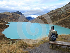 Soleness in mountainous lake landscape with woman on bench