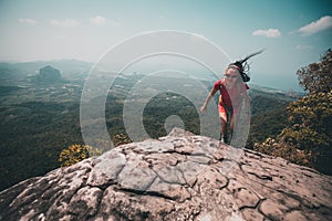 Backpacker running up on mountain top cliff edge