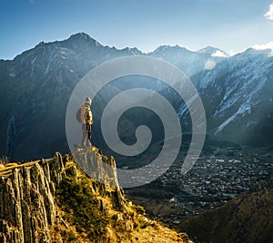 Backpacker sit on cliff edge and looks at mount valley