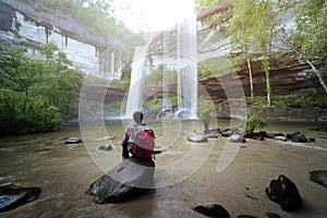 Backpacker sitting in front of waterfall