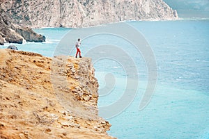 Backpacker standing on edge of cliff over sea.