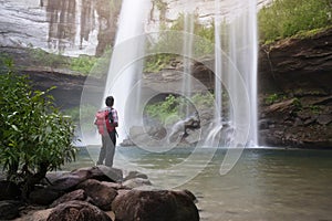Backpacker standing in front of waterfall