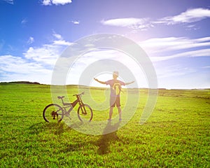 Backpacker standing next to bicycle with sunrise background