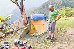 Backpacker standing tent morning mess gear disorder, camping mountains Bolivia.