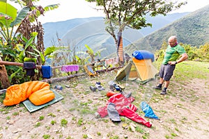 Backpacker standing tent morning mess gear disorder, camping mountains Bolivia.