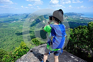 Backpacker taking photo with digital camera on mountain peak