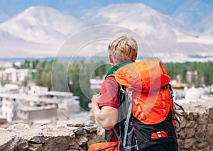 Backpacker tourist looks on blue mountain