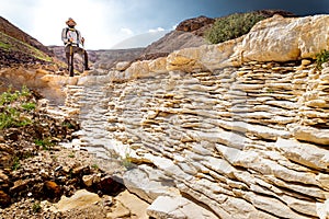 Backpacker tourist standing desert mountain cliff ridge edge landscape