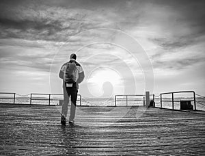 Backpacker tourist standing at sea on old wooden bridge