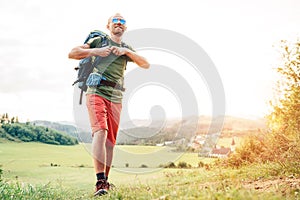 Backpacker traveler fastening sternum strap on backpack and preparing for trekking at summertime sunny day