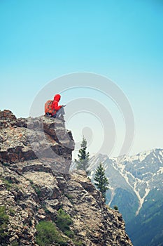 backpacker use digital tablet on mountain peak cliff