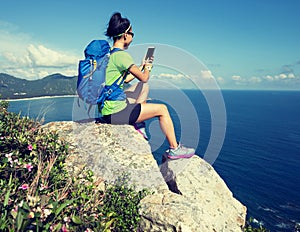 backpacker use smartphone on seaside mountain cliff edge