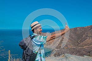Backpacker using his smartphone on vacation. man holding a cell phone with a sea in the background. Travel concept