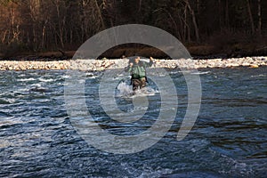 Backpacker wade rugged river