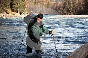 Backpacker wade rugged river