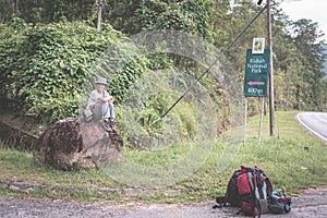 Backpacker waiting for hitchhike on the road for Kubah National Park, West Sarawak, Borneo, Malaysia.