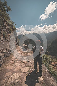 Backpacker walking on the Inca Trail above Machu Picchu, the most visited travel destination in Peru. Rear view, toned