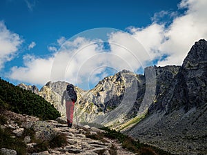 Batůžkář chůze po horské stezce s turistickými holemi