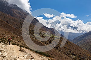 Backpacker walking mountain trail, Nepal village.