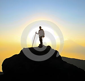 Backpacker with walking stick in sunset