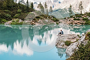 Backpacker woman with backpack enjoying the turquoise Lago di Sorapiss 1,925m altitude mountain lake view as he has mountain