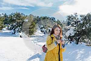 backpacker woman hiking outdoors in snowy mountain. Using mobile phone. Nature, technology and lifestyle