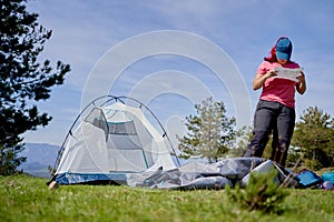 Backpacker woman setting up a tent outdoors in nature.