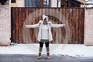 Backpacker woman walking in city during winter while snowing. Happy woman with arms outstretched enjoying outdoors