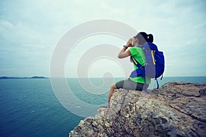 Backpacker yelling on seaside mountain top cliff