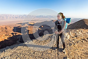 Backpacker young woman standing desert mountain edge canyon view