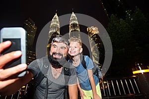 Backpackers in a big city. Father and son happy and excited together for the Malaysia trip. Having fun, taking selfies. Holidays