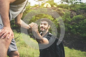 Backpackers man getting help to friend climb at nature,Helping hand,Overcoming obstacle concept