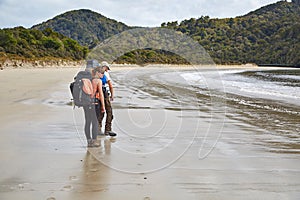 Backpackers walking on New Zealand sandy beach
