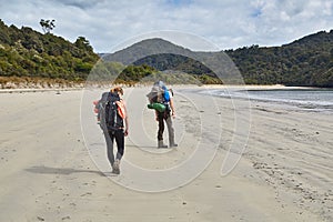 Backpackers walking on New Zealand sandy beach