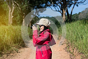 Backpacking Asian woman take a photo with digital camera in the morning at outdoor,Happy and smiling,Camping hiking concept