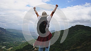 Backpacking female hiker stands on top of the mountain and enjoying the view. journey and success concept