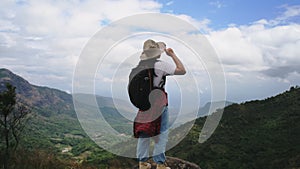 Backpacking female hiker stands on top of the mountain and enjoying the view. journey and success concept