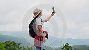 Backpacking female hiker stands on top of the mountain with raised arms and enjoying the view. journey and success concept