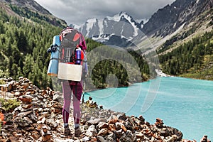 Backpacking woman enjoying view of majestic blue mountain lake in Altai