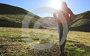 Backpacking woman hiking in sunrise mountains