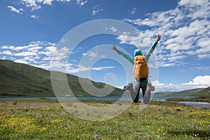 Backpacking woman jumping on flowers and grass