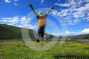 Backpacking woman jumping on flowers and grass