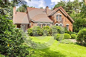 Backround yard of a beautiful english style house with bushes and green lawn. Real photo