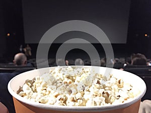 Backs of empty seats in a movie theater with a bowl of popcorns
