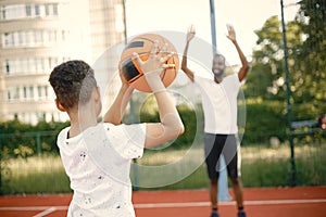 Backside photo of father with his son playing basketball in basketball court together