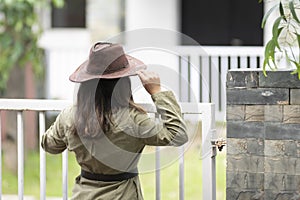 Backside portrait of an Indian young girl standing near a fence wearing garage mechanic attire and a cowboy hat. Indian lifestyle