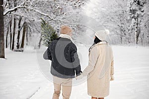 Backside portrait of romantic couple walking in forest at winter day