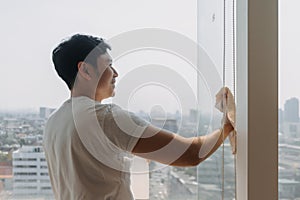 Backside view of asian Thai man wiping window glass in room apartment with city view, keep glass sparking clean